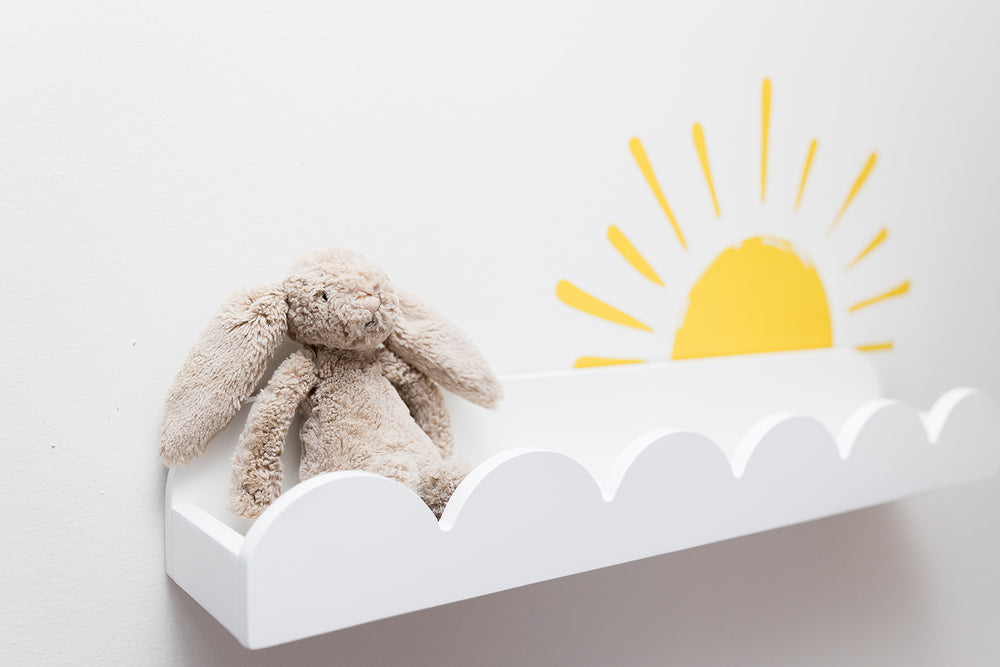 Plush bunny toy on a white shelf with a yellow sun reusable decal sticker on a light gray background