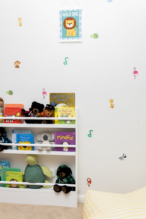Children's room with shelves filled with books and toys, reusable wall decal stickers of animal decorations.