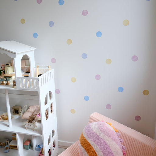 Children's room with a white dollhouse, colorful  reusable polka dot wall decal stickers, and pink bed.
