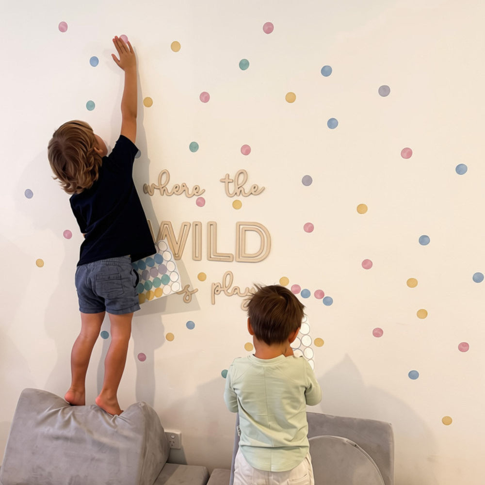 Video of to boys app;ying reusable pastel polka dot decal stickers to a white playroom wall