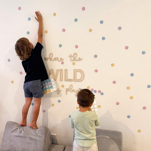 Video of to boys app;ying reusable pastel polka dot decal stickers to a white playroom wall