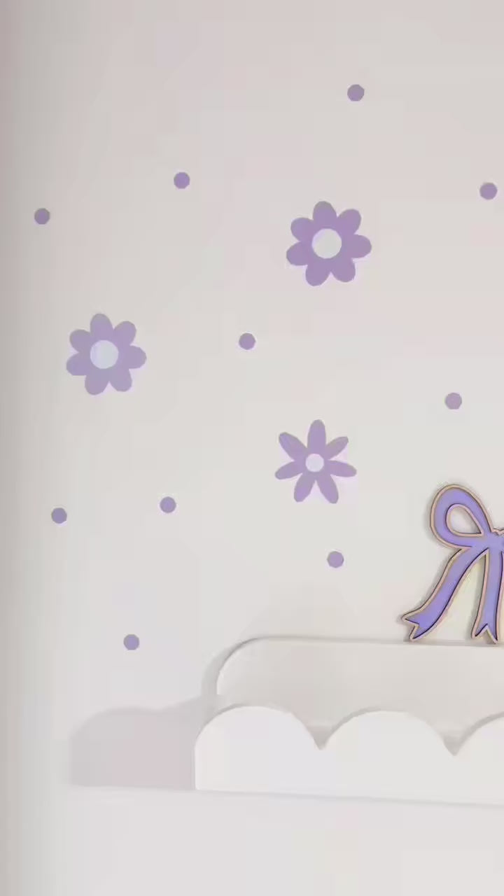 Video of Lilac Daisy reusable wall decal stickers on a white wall with a a scalloped white shelf