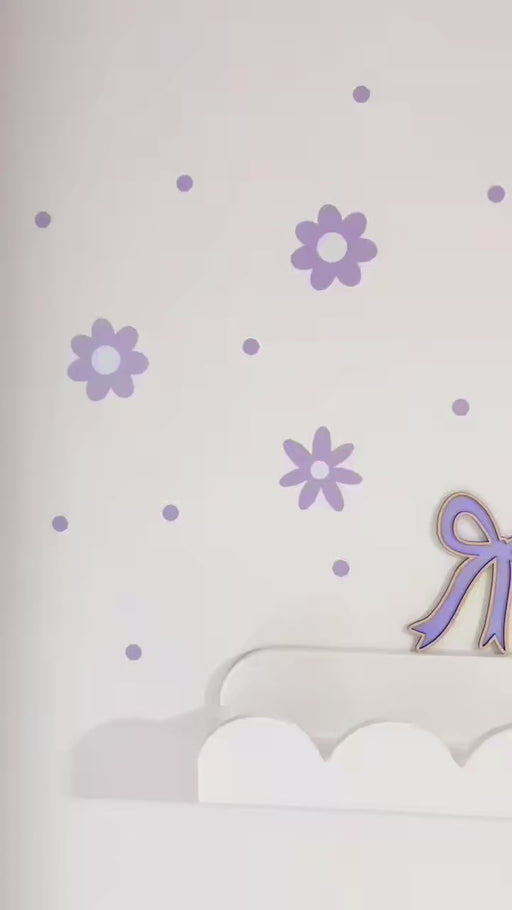 Video of Lilac Daisy reusable wall decal stickers on a white wall with a a scalloped white shelf
